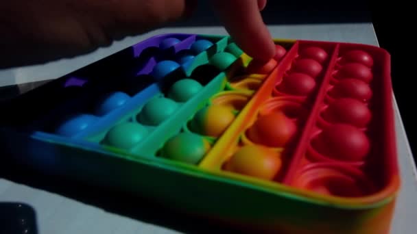 一个现代流行的玩具 时尚的抗压力感官玩具 简单的酒窝在孩子的手中 爆出五彩缤纷的气泡 — 图库视频影像