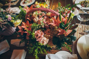 Büyük bir buket çiçek. Masanın üzerinde bir sepet zambak var.