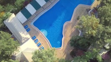 İnsansız hava aracı görüntüsü: Denizde yüzen bir adam. Suda bir yüzücü. Otelin yüzme havuzunun üst manzarası.