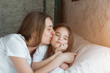 Sabah kızları: Çocuklu anne yatakta oynuyor. Bir rüyadan uyanmak. Daha yeni uyandım.