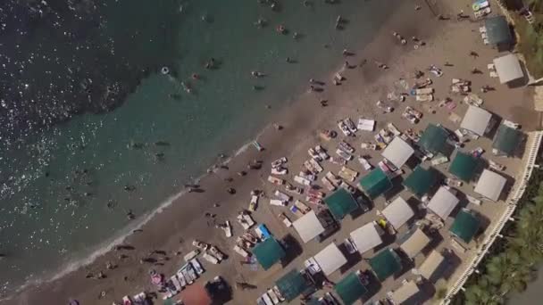 La mer avec un littoral étroit et de nombreux vacanciers sur la plage. tir à partir d'un drone : une plage de la ville. — Video