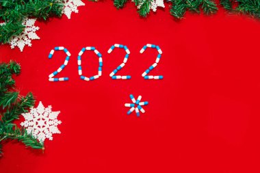 Coronavirus, ncov-19 ve yeni yıl. Kendini izole bir tatil, hastane. Noel süsleri, tıbbi aletler şırınga ve Noel Baba şapkası. Kırmızı arkaplanda boşluk kopyala