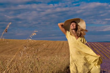 Hasat: Olgun buğday tarlada yetişir. Altın tahıl ve kız tarlada yürüyorlar. Sıcak güneş deriyi okşar.