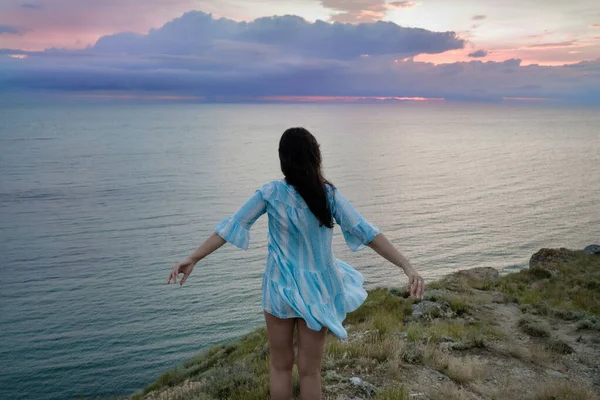 Uma mulher em uma rocha olhando para a distância contra o mar — Fotografia de Stock