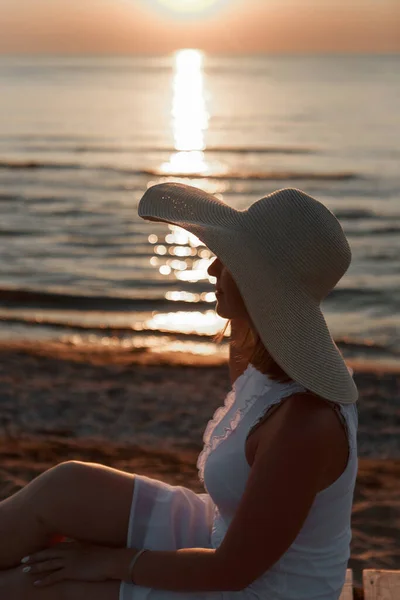 Reise til havet. En jente i kjole og hatt går langs stranden. En turist går langs kysten. varme reiser i ferieperioden. kopieringsareal – stockfoto