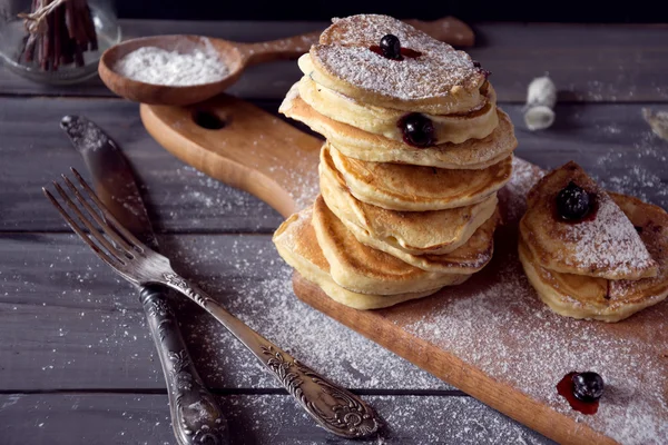 Stapel hausgemachter Pfannkuchen mit Beeren auf rustikalem Hintergrund. — Stockfoto