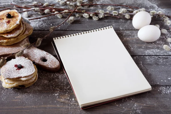 Pfannkuchen und leeres Rezeptbuch auf rustikalem Hintergrund — Stockfoto