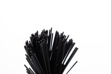 Pişmemiş siyah spagetti makarna beyaza izole edilmiş.