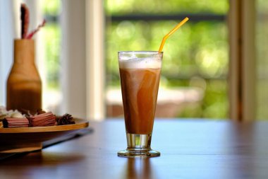 Close up of an iced coffee with cream and a straw