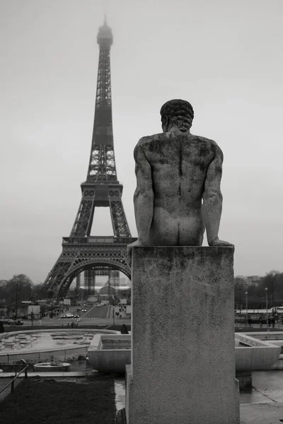 Black and white photo of a beautiful statue of a man near the Eiffel tower in Paris