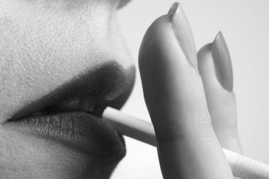 Şehvetli dudakları olan, siyah beyaz sigara içen bir kadının yakın çekimi.