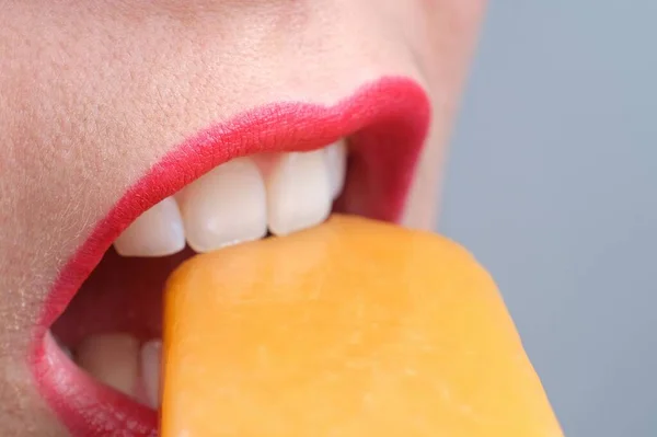 用红唇和美丽的白牙捂住一个年轻女人的嘴 咬着冰淇淋 — 图库照片
