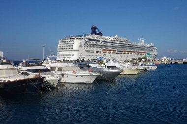 Mykonos, Yunanistan - 27 Temmuz 2016: Güneşli bir günde Yunanistan 'ın Mykonos Cyclades limanında büyük bir yolcu gemisi ve küçük özel botlar
