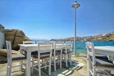 Ios siklades Yunanistan 'daki ünlü mylopotas plajının önündeki geleneksel ahşap sandalyeler ve masa