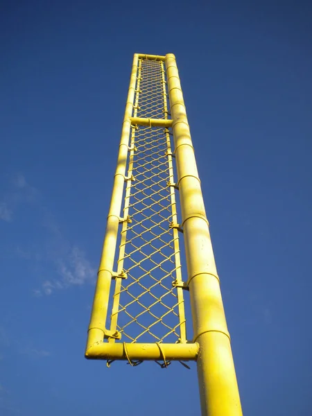 Yellow sports goal post against a blue sky at a sports field park