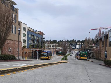 Kirkland, WA / USA - Ocak 2020: Şehir merkezindeki Kirkland Transit Merkezi manzarası King County Halk Kütüphanesi, kapalı otobüs durağının önünde boş bir otobüs bekliyor..