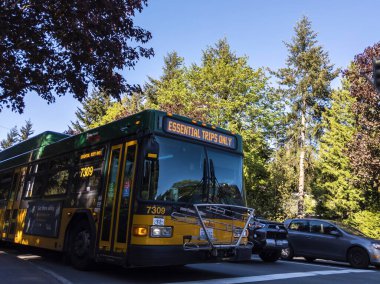 Kirkland, WA / USA - Mayıs 2020: Geçiş ekranında 'Sadece Temel Seyahatler' yazan King County Metro otobüsünün sokak görüntüsü.