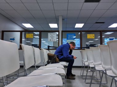 Bellevue, WA / USA - 1 Kasım 2019: Beyaz sandalyeli Bellevue Motorlu Taşıtlar Dairesi bekleme odası ve bekleyen bir adam.