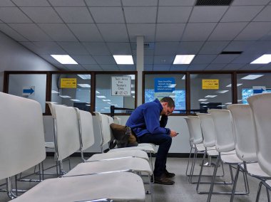 Bellevue, WA / USA - November 1st, 2019: Bellevue DMV waiting room with white chairs and a man sitting waiting. clipart