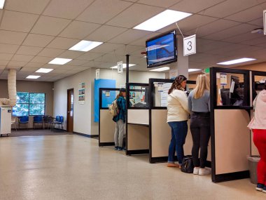 Bellevue, WA / USA - November 1st, 2019: People renewing license ID at counter at the DMV in Bellevue, WA clipart