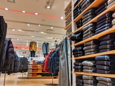 Bellevue, WA / USA - 1 Kasım 2019: Birçok farklı sonbahar ve kış kıyafetlerinin sergilendiği ve satışa sunulduğu bir alışveriş merkezindeki Uniqlo giyim mağazasının içi.