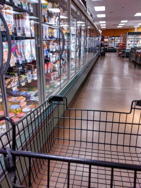 Kirkland, WA / USA - Kasım 2019: Bir alışveriş arabasının soğutulmuş et ve peynirlerin yanındaki QFC marketinde gezinirken kısmi görüntüsü..