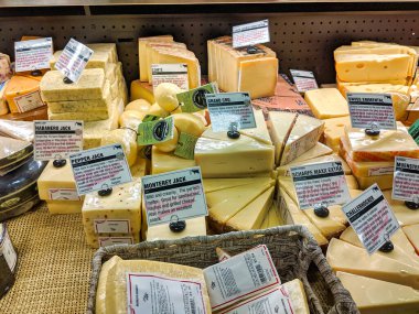 Kirkland, WA / USA - Aralık 2019: Kirkland QFC marketinin içindeki şarküteride sergilenen çeşitli peynir parçalarının görüntüsü.