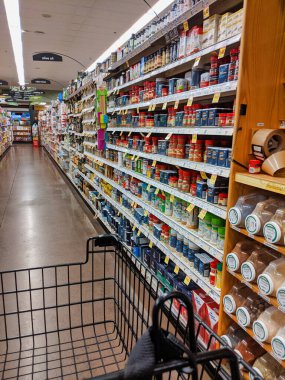 Kirkland, WA / USA - Kasım 2019: Baharat, baharat, baharat ve yağ reyonunda, QFC bakkalında seyir halindeki bir alışveriş arabasının kısmi görüntüsü.