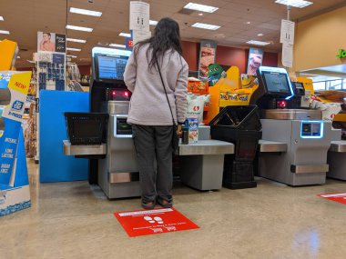 Kirkland, WA / USA - Mart 2020 civarı: Washington 'daki barınak sırasında Safeway' deki bir marketin kendi kendine kontrol çizgilerinde toplumsal uzaklık talimatı veren işaretler