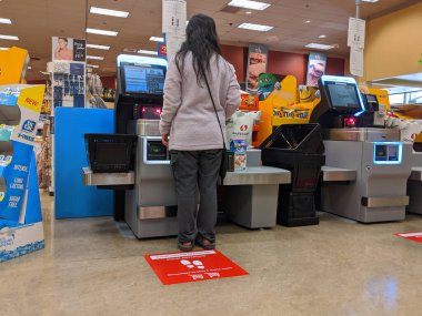 Kirkland, WA / USA - Mart 2020 civarı: Washington 'daki barınak sırasında Safeway' deki bir marketin kendi kendine kontrol çizgilerinde toplumsal uzaklık talimatı veren işaretler