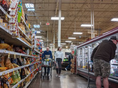 Kirkland, WA / USA - Mart 2020: Genç bir kadın COVID-19 salgınının ortasında yaşlı bir adamla çip ve dondurucu gıda reyonunda alışveriş yapıyor.