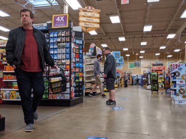 Kirkland, WA / USA - Nisan 2020: Fred Meyer 'in marketinde yüz maskesi takmış müşteriler, güvenlik için yere yapıştırılmış sosyal mesafe etiketleri ile