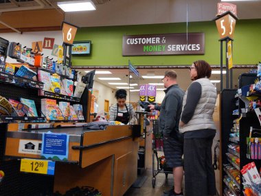 Kirkland, WA / USA - Nisan 2020 civarı: Koronavirüs salgını sırasında Fred Meyer 'in bakkal dükkanının kasasında bir pleksiglass duvarın arkasında kasiyer