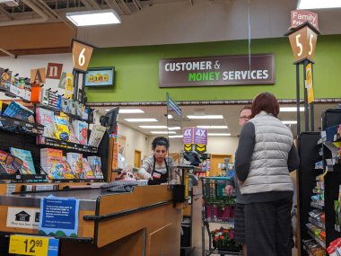 Kirkland, WA / USA - Nisan 2020 civarı: Koronavirüs salgını sırasında Fred Meyer 'in bakkal dükkanının kasasında bir pleksiglass duvarın arkasında kasiyer