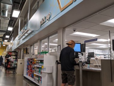 Kirkland, WA / USA - Nisan 2020 civarı: COVID-19 Coronavirus salgını sırasında bir bakkaldaki ecide maskeli yaşlı bir adam bekliyor.