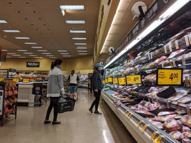Kirkland, WA / USA - Nisan 2020: Safeway 'deki bir markette et bölümünde koruyucu maskeler takan kadınlar.