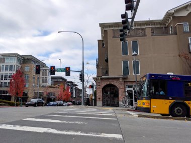 Kirkland, WA / USA - Kasım 2019: Bulutlu bir günde kütüphane yakınlarındaki bir kavşaktan geçen araba ve otobüs trafiği.