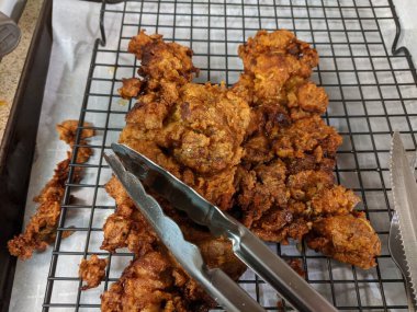 Çıtır çıtır, kızarmış tavuk butları, siyah tel askıda soğutma.