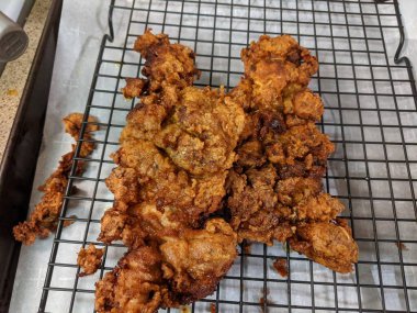 Çıtır çıtır, kızarmış tavuk butları, siyah tel askıda soğutma.