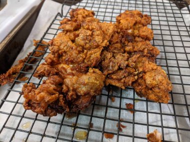 Çıtır çıtır, kızarmış tavuk butları, siyah tel askıda soğutma.