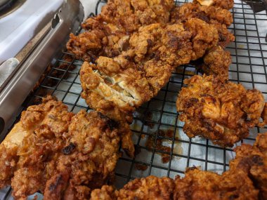 Çıtır çıtır, kızarmış tavuk butları, siyah tel askıda soğutma.