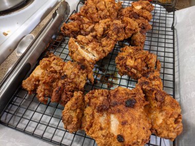 Çıtır çıtır, kızarmış tavuk butları, siyah tel askıda soğutma.