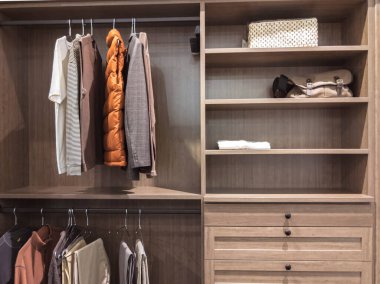 Büyük, dolapta gömlekler ve pantolonlar askıda asılı ve ayakkabılar rafta asılı.