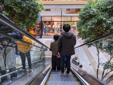 Bellevue, WA USA - Mart 2021: Bellevue Alışveriş Merkezi 'nde yürüyen merdivenden inen yüz maskesi takan insanlar