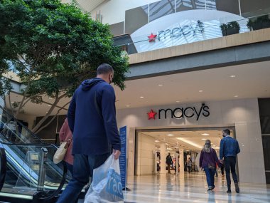 Bellevue, WA USA - Mart 2021 civarı yüz maskeli müşteriler Bellevue Alışveriş Merkezi 'ndeki bir Macy mağazasının girişine yaklaşıyorlar..