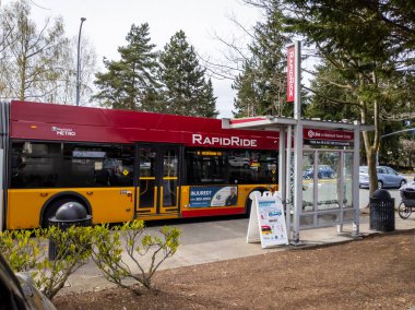 Redmond, WA USA - Nisan 2021: Güneşli bir günde otobüs durağında duran hızlı bir metro otobüsünün görüntüsü.