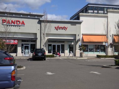 Kirkland, WA USA - Nisan 2021: Totem Gölü 'ndeki bir Xfinity mağazasının önündeki bankta oturan bir kadının görüntüsü.