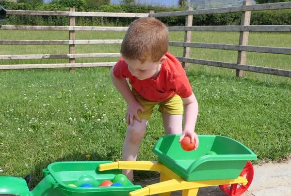 Red Headed Dziecko Bawiące Się Zabawkami Ogrodzie — Zdjęcie stockowe
