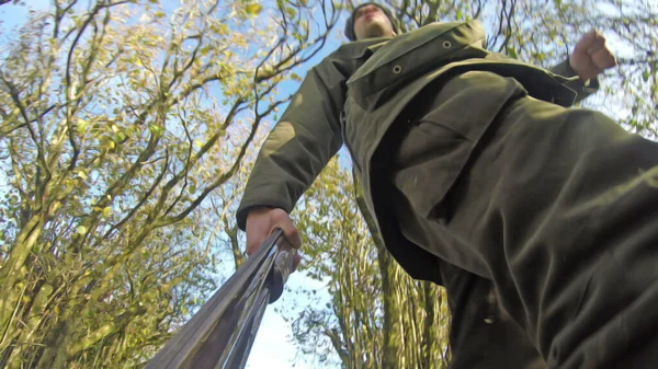 Hunter walking in the woods with camera on the end of gun