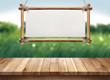 Yeşil doğa üzerindeki ahşap işareti asılı ile ahşap masa arka plan bulanık